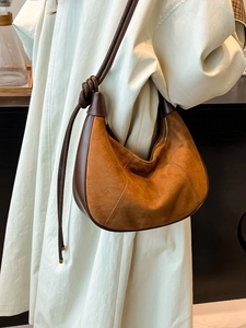 Retro brown suede half-moon crossbody bag with decorative knot strap shown on model