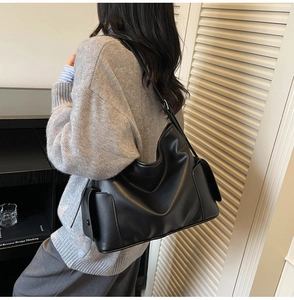 Detail of the black large tote bag showing smooth synthetic leather and decorative side straps