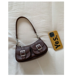 Detailed close-up of dark brown lychee grain leather and silver buckles on a shoulder bag