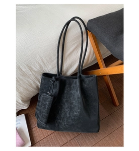 Close-up of black textured leather tote bag with PAN TOR branding and mini pouch detail