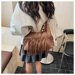 Detail of brown suede crossbody bag featuring silver star studs and bohemian fringe trim