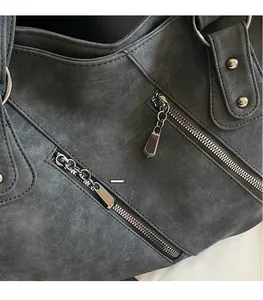 Détail du sac cabas en daim gris foncé avec fermetures éclair et rivets métalliques