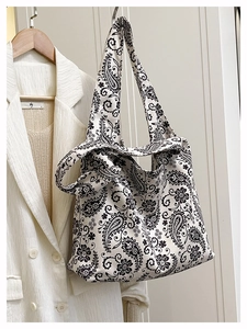 Close-up of canvas tote bag featuring black and white paisley pattern and wide strap