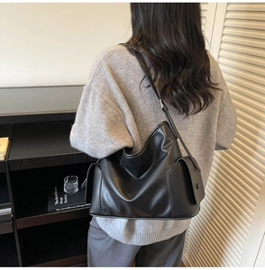 Detail of the black large tote bag showing leather texture and practical side pocket