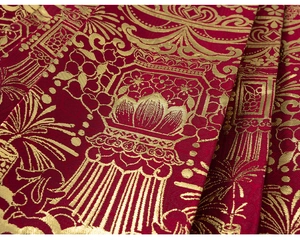 Close-up of red Chinese brocade fabric with golden floral embroidery and jacquard texture