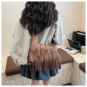 Detail of vintage brown suede crossbody bag with star rivets and long stylish tassels
