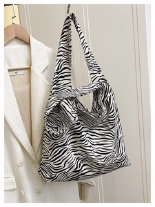 Detail view of stylish zebra print canvas tote bag hanging next to a white blazer