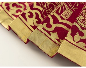 Macro detail of red silk fabric with golden auspicious clouds pattern for Lunar New Year clothes