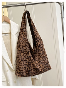 Detailed view of leopard print tote bag hanging with white blazer backdrop