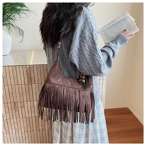 Detail of dark brown suede crescent bag with vintage metal rivets and long tassels