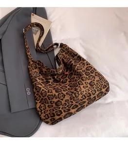 Dettaglio della borsa tote leopardata con tracolla regolabile su sfondo blazer grigio