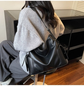 Detail view of a black large capacity leather hobo bag showing soft texture and side pockets