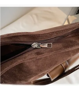 Close-up of smooth metal zipper on dark brown suede shoulder bag for women