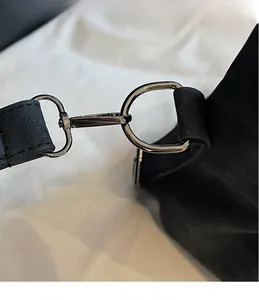 Détail du crochet métallique foncé sur un grand sac à bandoulière noir mat de qualité