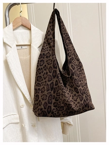 Detail of large leopard print tote bag hanging on a rack with fashion apparel background