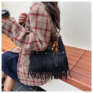 Detail of bohemian black suede crossbody bag with fringe tassels and silver star rivets
