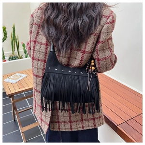 Close-up of black fringe crossbody bag with star rivets and bohemian wooden beads