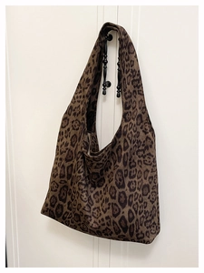 Detail of leopard print tote bag showing fabric texture and shoulder strap construction