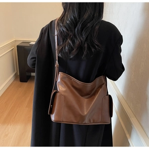 Detail view of large dark brown leather tote bag showing side pocket and matte texture