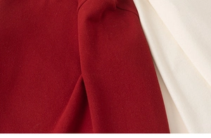Detailed close-up of thick red wool fabric texture with contrast beige stitching detail