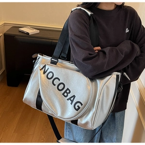 Vista dettagliata della grande borsa metallica argento con logo NOCOBAG nero e tracolla larga