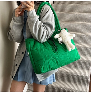 Detail of green quilted puffer tote bag with cute white rabbit charm and drawstring
