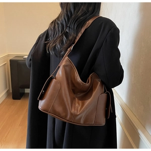 Detail view of large brown leather tote bag with side pockets during daily commuting