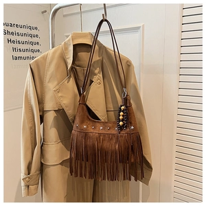 Detail of brown suede tassel bag with silver star studs and bohemian fringe details