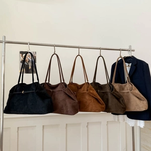 Detailed row of large suede tote bags in various earthy colors hanging on a rack