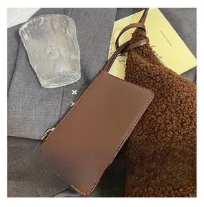 Detailed macro view of a brown leather phone bag with yellow contrast stitching and metal zipper