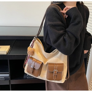 Close-up of beige canvas tote bag featuring brown leather pockets and a cute bear charm