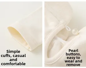 Detailed close-up of cream children's cloak with pearl buttons and soft ribbed cuffs