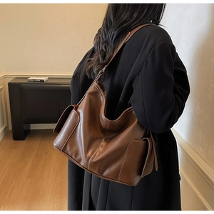 Macro view of brown vintage PU leather tote bag featuring functional side flap pockets