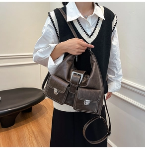 Detail shot of vintage brown tote bag with contrast stitching and decorative buckles