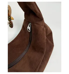Close-up of brown suede hobo bag fabric texture with zipper and wooden bead charm