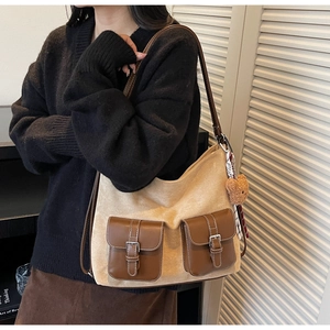 Detail view of large bicolor tote bag with front buckle pockets and brown straps