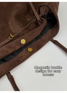 Detail of dark brown suede tote bag with magnetic closure and gold-tone hardware