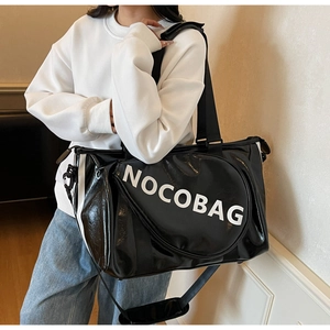 Dettaglio della borsa da viaggio nera lucida con logo NOCOBAG e tracolla regolabile rimovibile