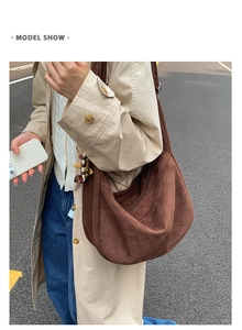 Deep brown suede hobo shoulder bag with a wide strap shown in an urban street style view