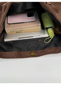Macro view of spacious brown suede tote interior with books, tablet, and magnetic snap
