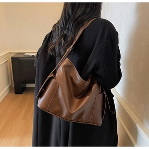 Detailed shot of a vintage brown leather tote bag showing side flap pockets and texture