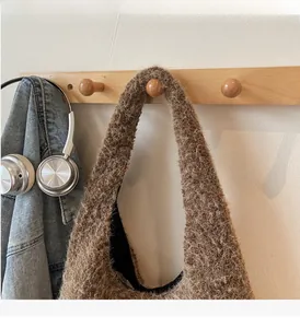 Détail de la texture d'un sac cabas en fausse fourrure marron suspendu à un crochet en bois