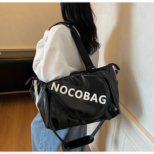 Dettaglio di una borsa sportiva nera in vernice con grande logo NOCOBAG su un modello