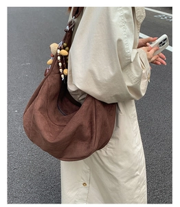 Detail of dark brown faux suede crescent bag with ethnic wooden bead charm accessory