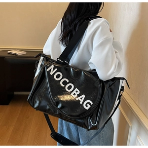 Borsa da viaggio NOCOBAG nera lucida indossata da un modello per sport e fitness