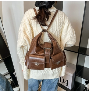 Detail view of brown vintage PU leather backpack with metallic buckles and front pockets