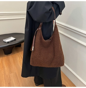 Detail of plush brown faux fur tote bag with leather strap worn by model in black coat