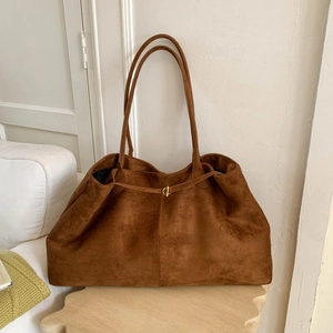 Close-up of caramel suede tote bag featuring a gold metal ring buckle and fine texture