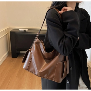 Brown vintage leather tote bag with side flap pockets shown on a model for daily commute