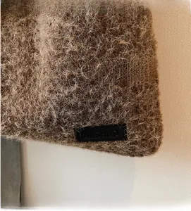 Gros plan sur la texture mohair marron moelleuse et étiquette en cuir noir avec logo